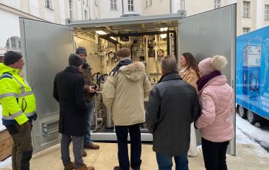 Interessierte Gäste schauen sich eine technische Anlage in einem Container an.