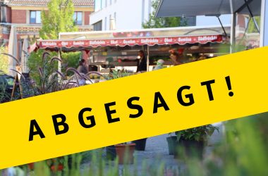 Ein geber Banner mit der Aufschift: Abgesagt! Im Hintergrund ist ein grüner Markt.