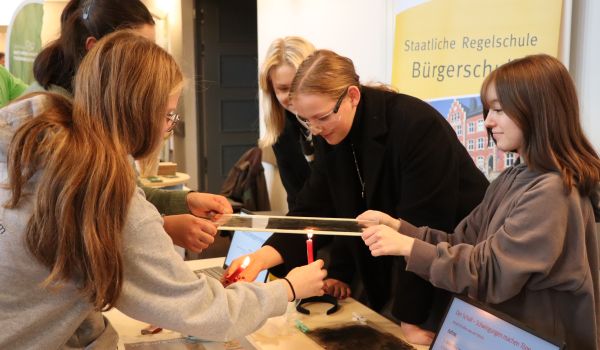 Jugendliche halten eine Folie über eine Kerze.