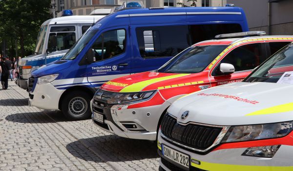 Ein Feuerwehr-, Polizei- und THW-Auto stehen nebeneinander.
