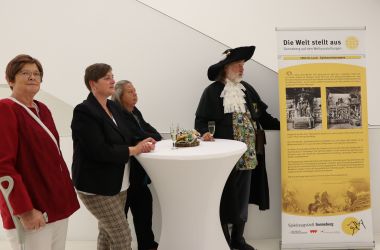 Vier Personen stehen neben einem Geschichtsbanner.