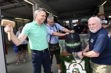 Ein Mann schlägt mit einem Hammer einen Zapfhahn in ein Bierfass. Es ist der Bürgermeister der Stadt Sonneberg.
