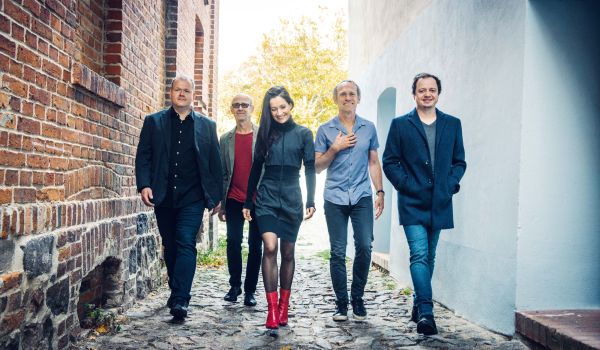 Vier Männer und eine Frau laufen durch eine Gasse.