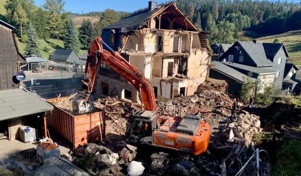 Ein Bagger reißt ein Haus ein.