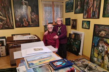 Ein Mann und eine Frau in einem Raum, umgeben von vielen Gemälden.