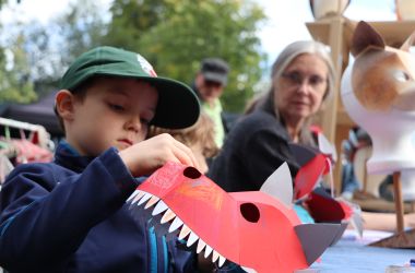 Ein Kind bastelt eine Maske aus Papier.