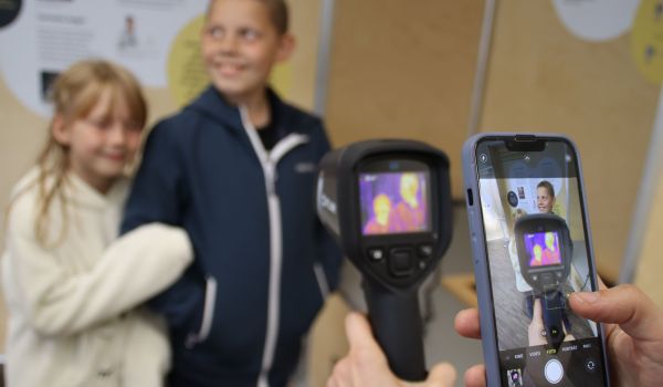 Eine Person macht mit ihrem Smartphone ein Bild von den Aufnahmen einer Infrarotkamera.