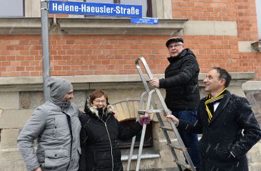 Vier Personen bringen ein Schild an.