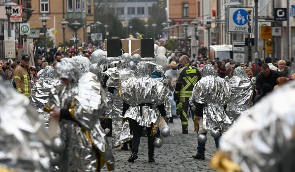Menschen in Silberfolie gewickelt laufen beim Umzug mit.