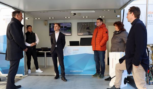 Fünf Menschen stehen auf der Ausklappfläche eines Anhängers.