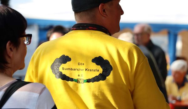 Ein Mann mit einem gelben T-Shirt. Auf dem Rücken steht: Dös Sumbarcher Kranzla e.V..
