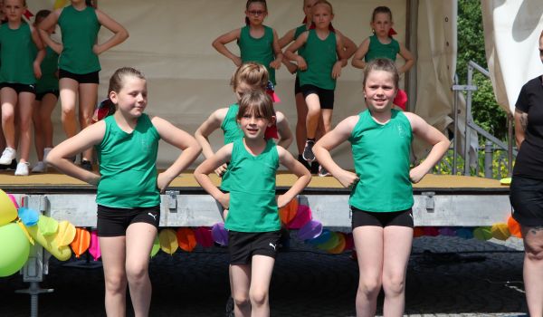 Kinder tanzen auf und vor einer Bühne.