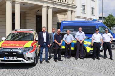 Ein Feuerwehr-, Polizei- und THW-Auto stehen auf dem Platz vor dem Sonneberger Rathaus. Davor stehen die jewiligen Mitarbeiter sowie der Bürgermeister und der Beigeordnete.