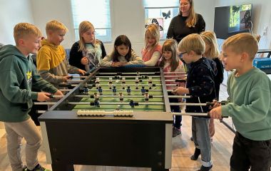 Mädchen und Jungen an einem Tischkicker-Spiel.