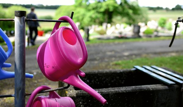 Eine Gießkanne auf einem Friedhof.