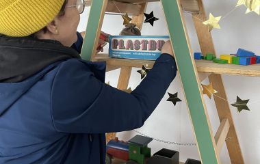 Eine Frau dekoriert ein Regal mit Spielsachen.