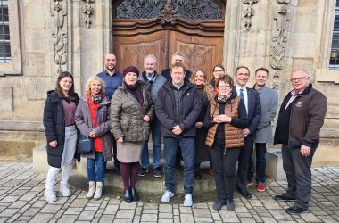Eine Gruppe von Männern und Frauen steht vor dem Eingang eines Klosters.