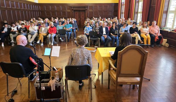 Ein Mann und zwei Frauen sitzen vor einem Publikum.