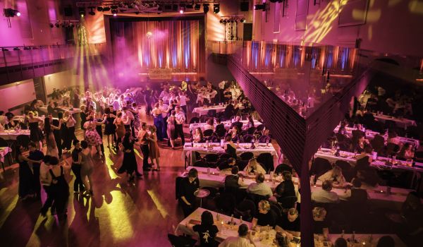 Menschen tanzen in einem großen Saal.