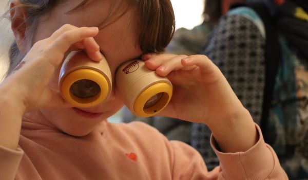 Ein Kind hält sich zwei Prismen vor die Augen.