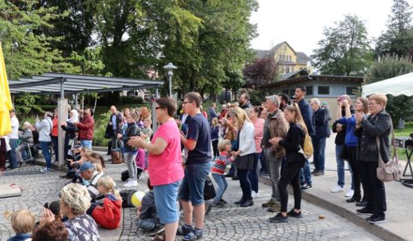 Menschen stehen auf einem gepflasterten Bereich im Stadtpark Sonneberg. Es scheint die Sonne.