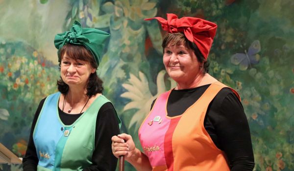 Zwei Frauen als Reinigungskräfte gekleidet stehen nebeneinander.