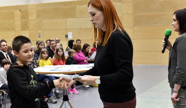 Eine Frau übergibt einen Gutschein an ein Kind.