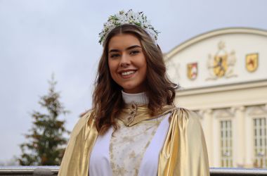 Eine Frau ist als Christkind gekleidet. Im Hintergrund ist das Rathaus der Stadt Sonneberg.