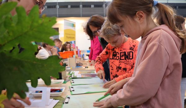 Kinder malen an einem Stand.