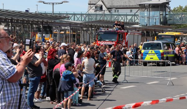 Viele Menschen stehen hinter einer Absperrung vor dem Bahnhof.