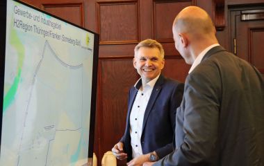 Zwei Männer stehen vor einem Bildschirm.