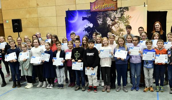 Viele Kinder stehen in einer Sporthalle und halten eine Urkunde in den Händen.