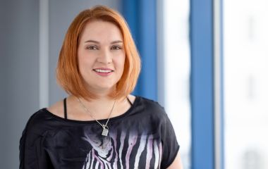 Eine Frau steht vor einem Fenster. Es ist die Bibliotheksmitarbeiterin und stellvertretende Einrichtungsleiterin Elisabeth König.