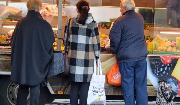 Drei Pesonen stehen an einem Verkaufsauto.