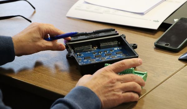 Ein Mann schaut sich ein Technikbauteil an.