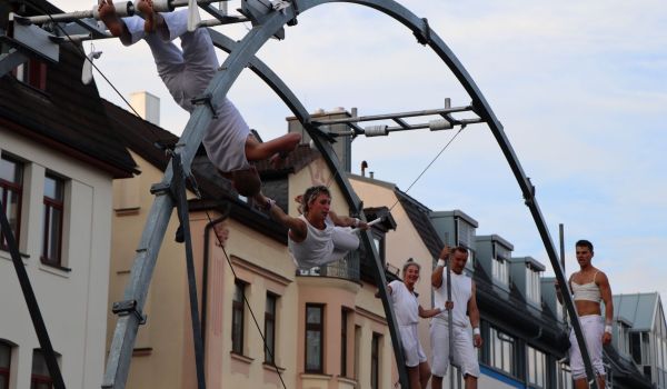 Mehrere Artisten turnen an einer hohen Metallkonstruktion.