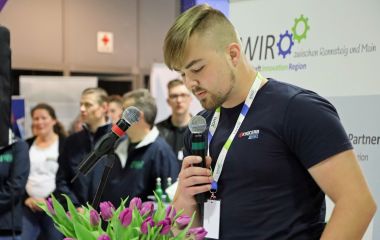 Ein junger Mann spricht in ein Mikrofon.