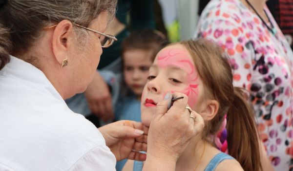 Ein Kind wird von einer Frau an einem Stand geschminkt