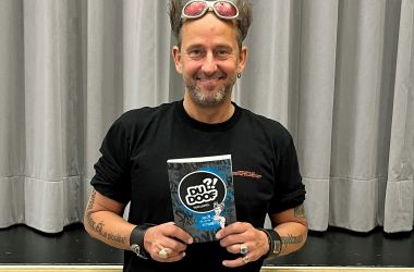 Ein Mann mit einem Buch steht vor einer Bühne.