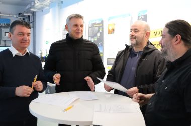 Vier Männer unterhalten sich an einem Stehtisch.