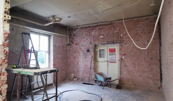 Eine Baustelle in einem Gebäude. Kabel hängen von der Decke.