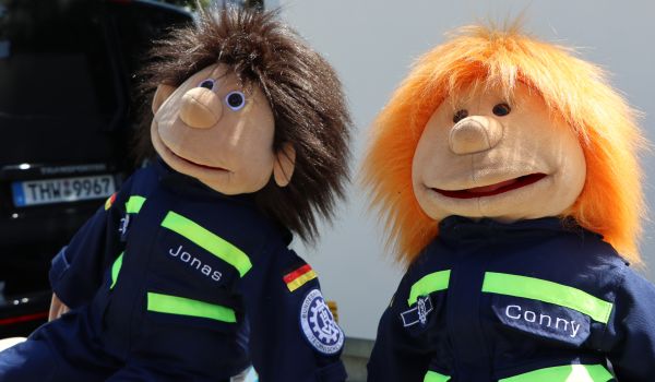 Zwei Bauchredner-Puppen in THW-Uniform.