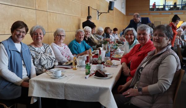 Frauen sitzen an gedeckten Tischen.