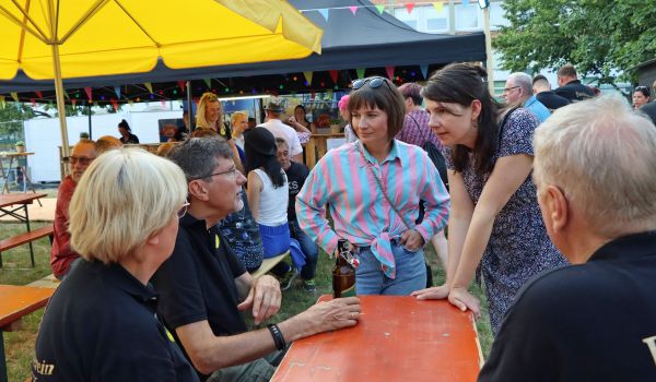 Menschen an Bierzeltgarnituren unterhalten sich.
