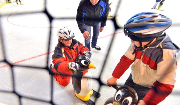 Kinder lernen Schlittschuh-Fahren.