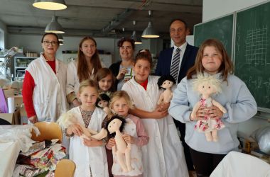 Fünf Kinder halten ihre selbstgebastelten Pupen in den Händen. Dahinter steht der 1. Beigeordnete Christian Dressel und drei Frauen.
