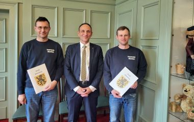 Zwei Feuerwehrkameraden erhalten eine Ernennungsurkunde.