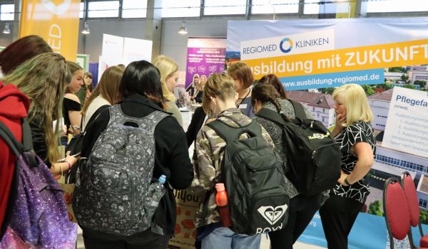 Jugendliche stehen an einem Infostand. Im Hindergrund ist ein Banner mit der Aufschrift: Regiomed Kliniken - Ausbildung mit Zukunft.