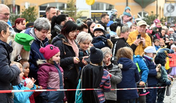 Kostümierte Kinder und Erwachsene stehen an der Straße und beobachten den Umzug.