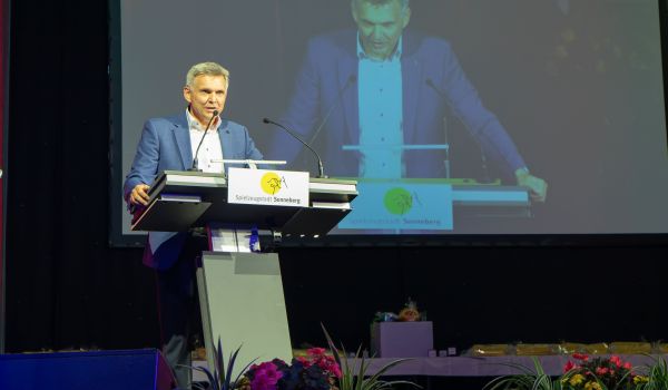 Der Bürgermeister steht an einem Rednerpult und begrüßt die Gäste.